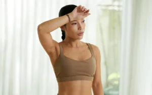 Woman wiping forehead after sweating, illustrating hyperhidrosis and treatment options at Natural Beauty Clinic White Rock
